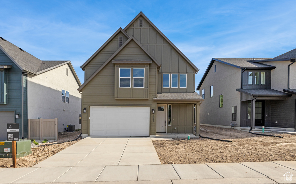View of front of house featuring board and batten siding, an attached garage, driveway, and cooling unit