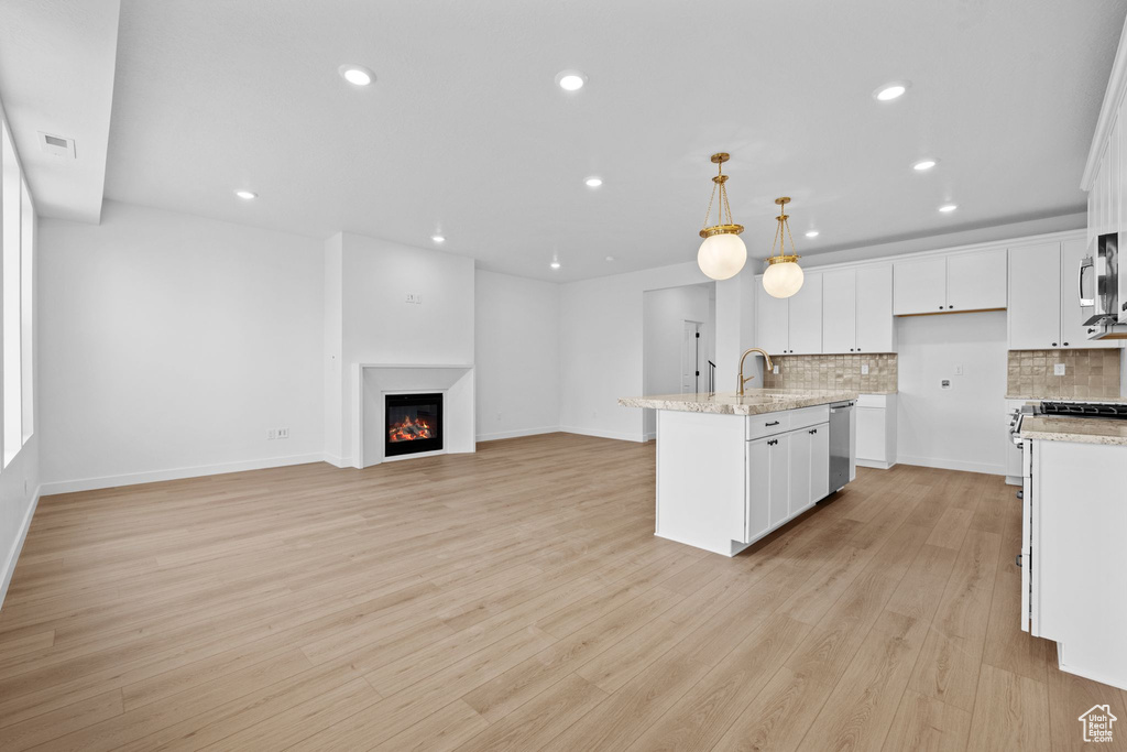 Kitchen featuring stainless steel dishwasher, tasteful backsplash, white cabinets, recessed lighting, and light wood-type flooring