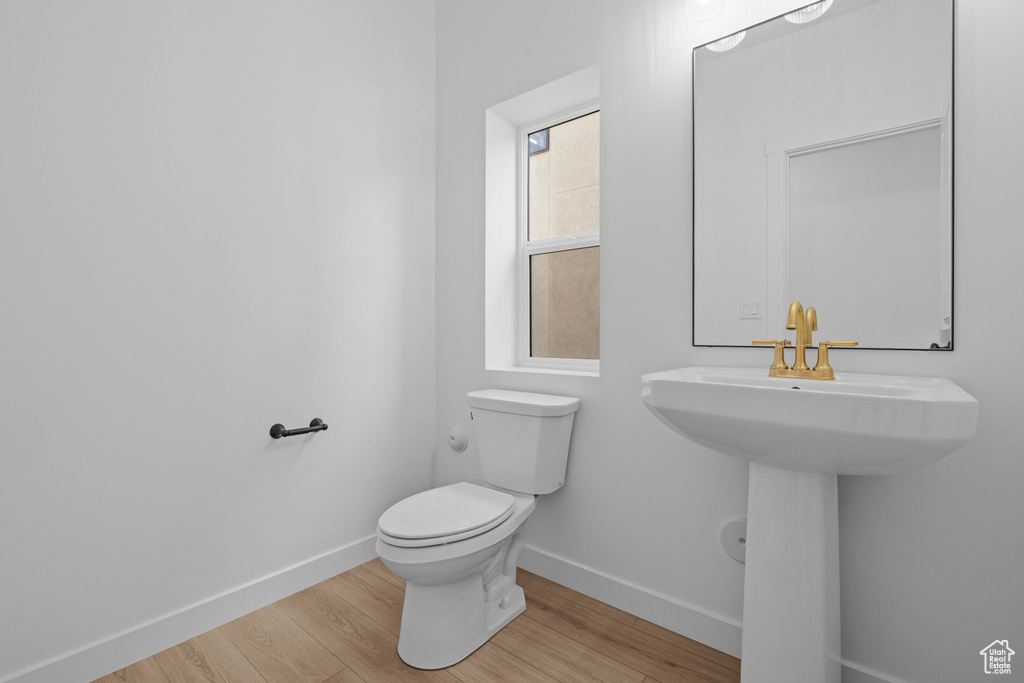Bathroom featuring baseboards, toilet, and wood finished floors