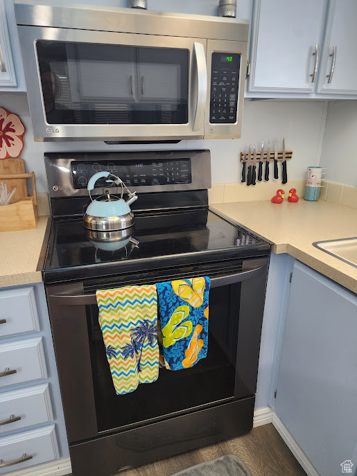 Kitchen with range with electric cooktop, stainless steel microwave, light countertops, and white cabinetry