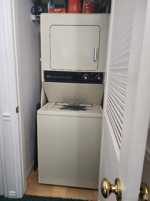 Washroom featuring stacked washer and clothes dryer and baseboards