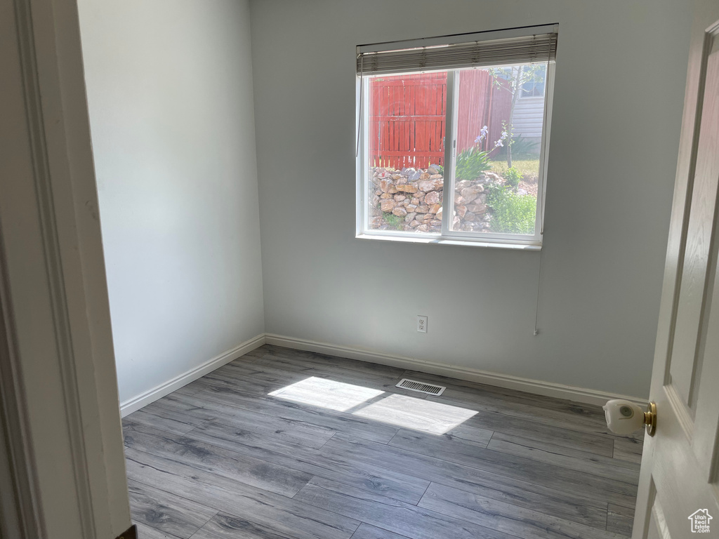 Empty room featuring wood finished floors, healthy amount of natural light, and baseboards
