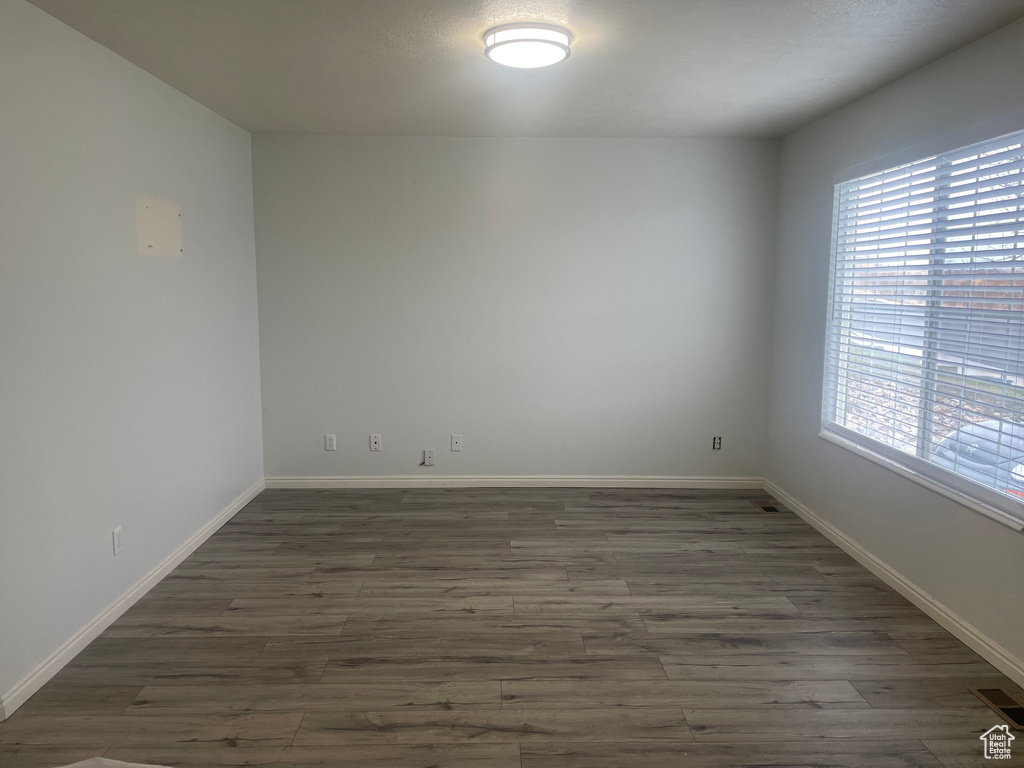 Spare room with dark wood-style floors and baseboards