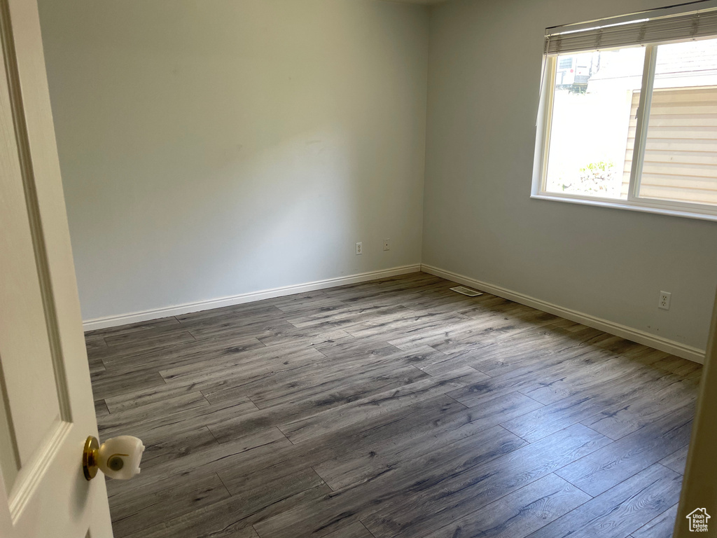 Unfurnished room with dark wood-style flooring and baseboards