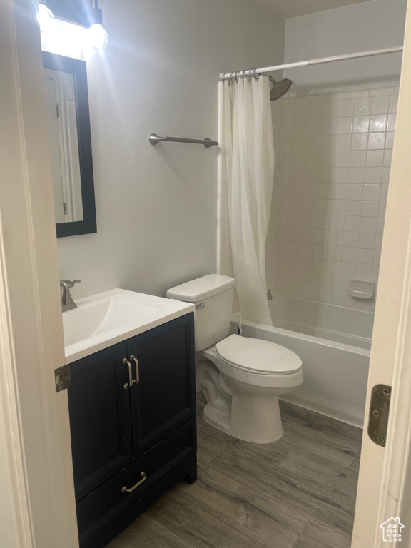 Full bath with vanity, toilet, shower / bath combination with curtain, and wood finished floors
