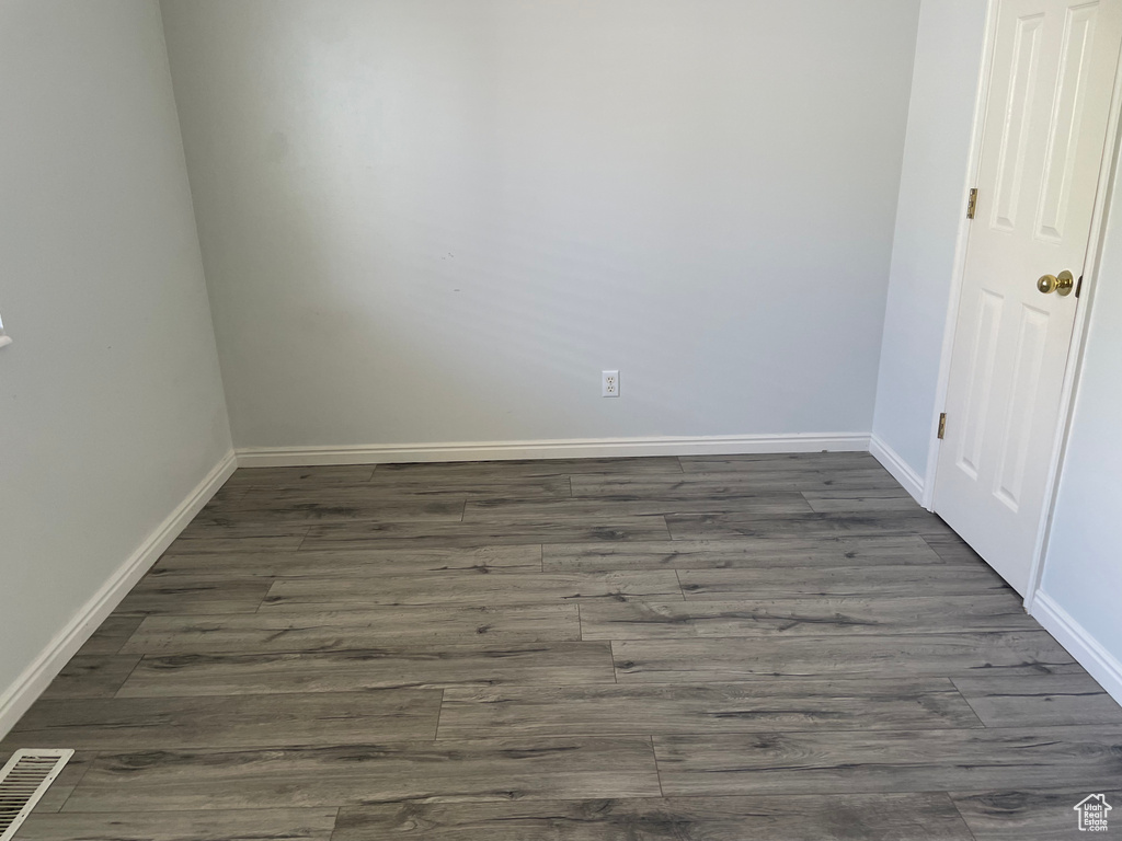 Spare room featuring dark wood-style floors and baseboards