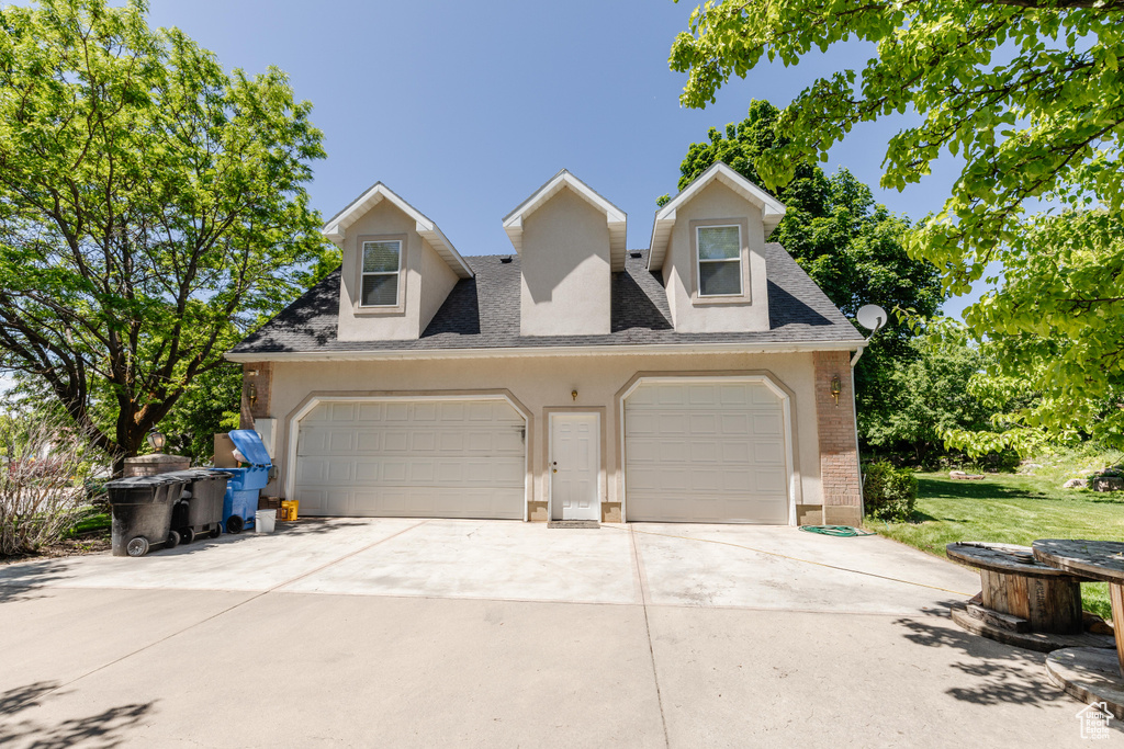 View of front of home featuring brick siding, driveway, a shingled roof, and an attached garage