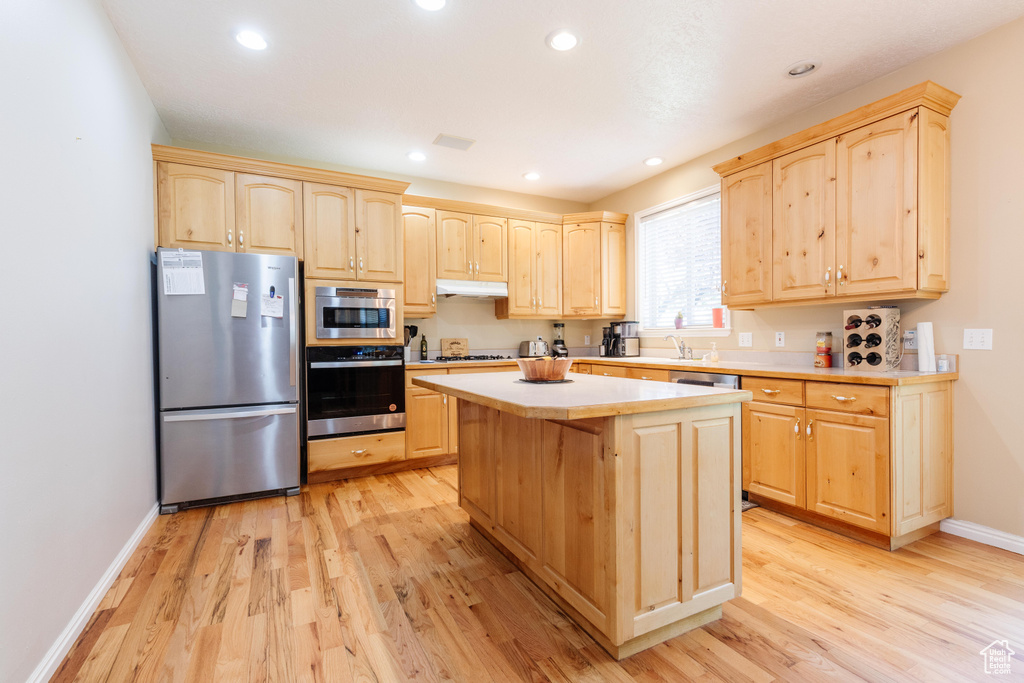 Kitchen with freestanding refrigerator, light brown cabinetry, light wood-style flooring, light countertops, and recessed lighting