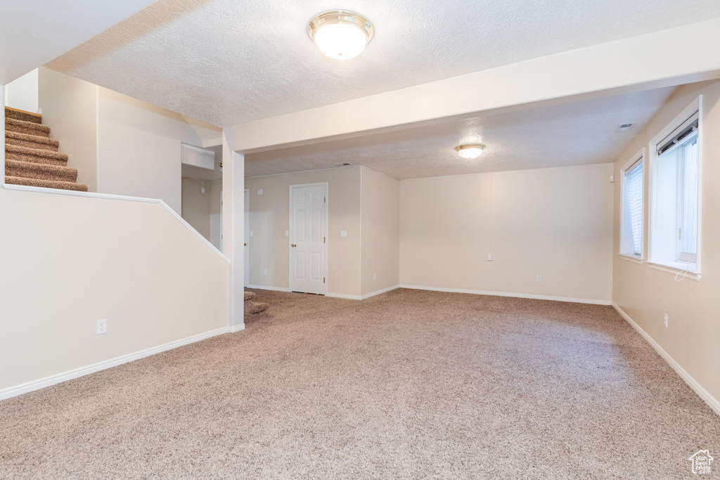 Carpeted spare room with a textured ceiling, stairway, and baseboards