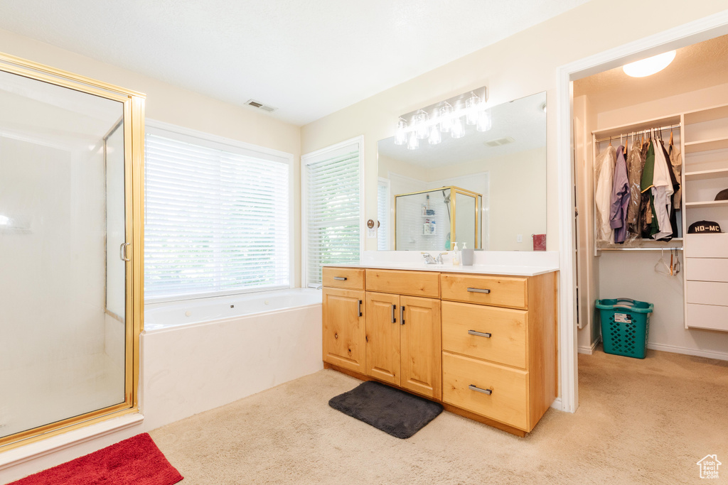 Bathroom with a stall shower, vanity, a bath, carpet floors, and a spacious closet