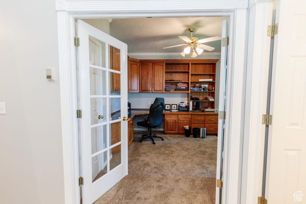Office featuring light colored carpet, a ceiling fan, french doors, a textured ceiling, and built in desk