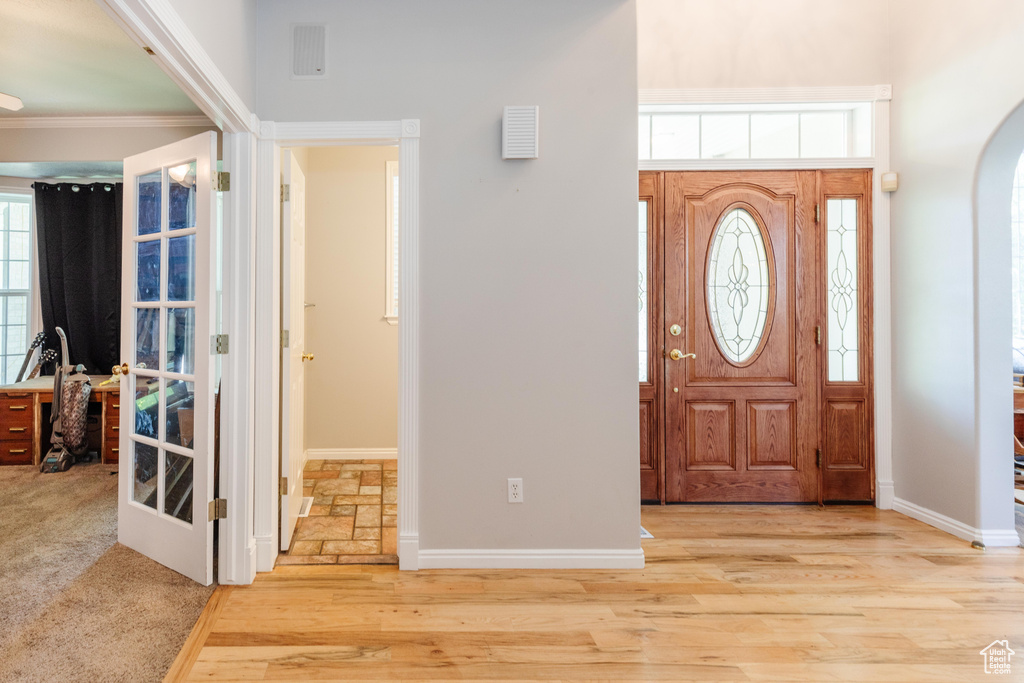 Foyer with baseboards, arched walkways, crown molding, and wood finished floors