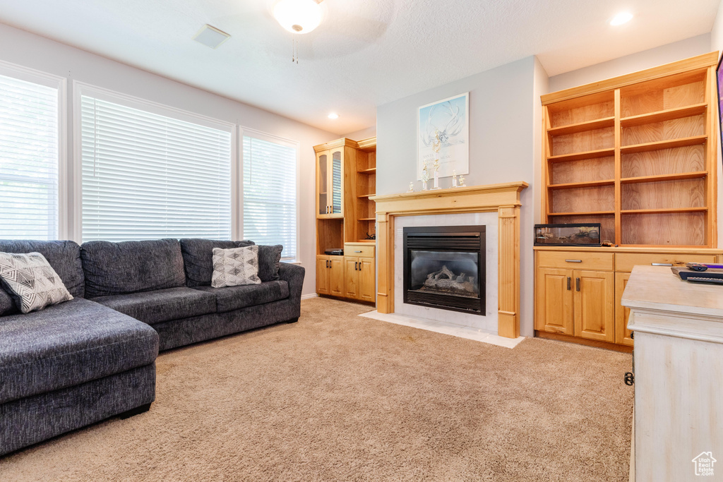Living room with light colored carpet, a fireplace with flush hearth, ceiling fan, and recessed lighting
