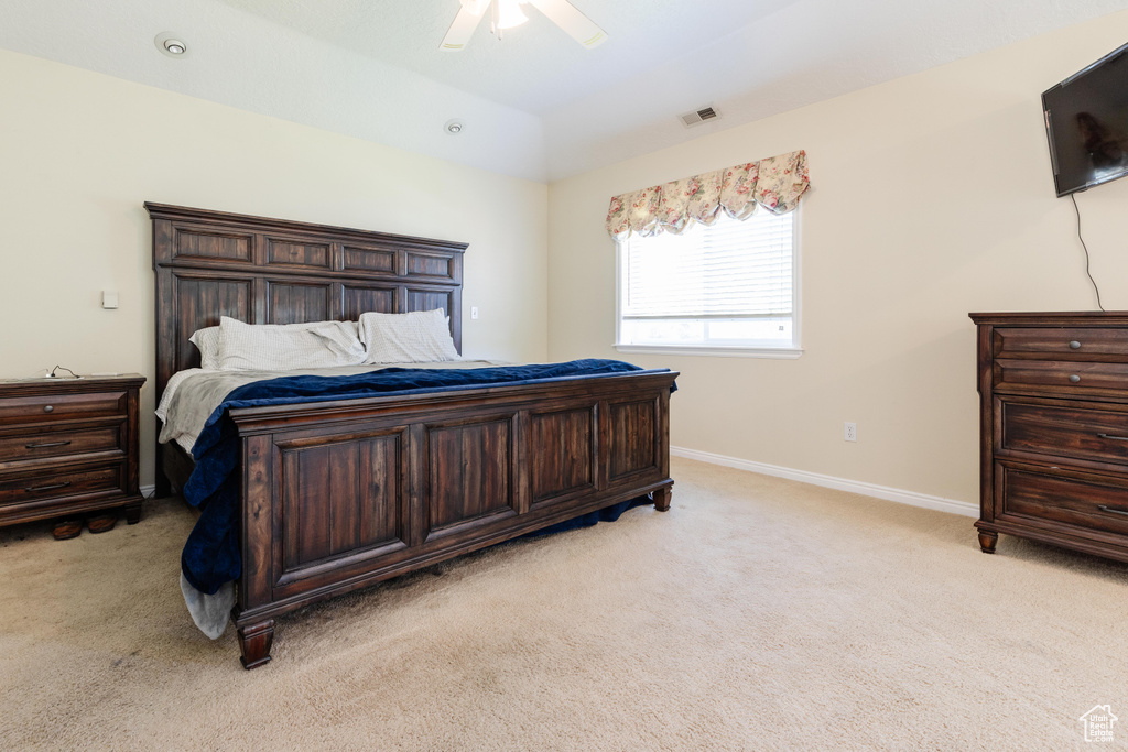 Bedroom with light colored carpet, baseboards, and ceiling fan
