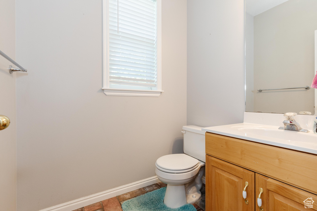 Half bathroom featuring baseboards, vanity, and toilet