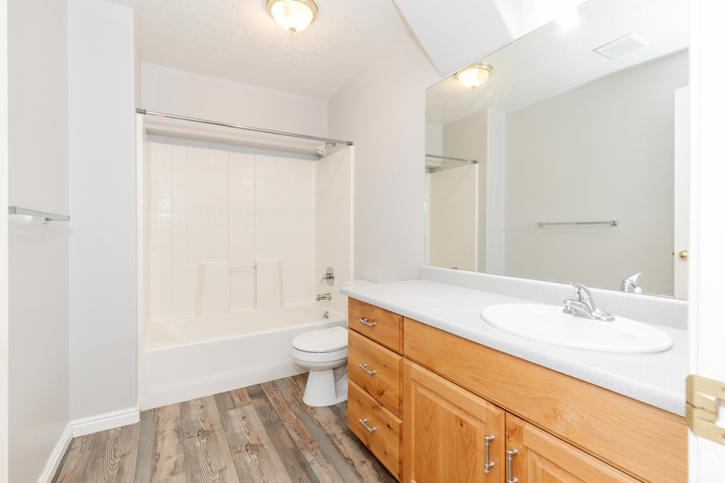 Full bathroom with vanity, wood finished floors, shower / washtub combination, and toilet