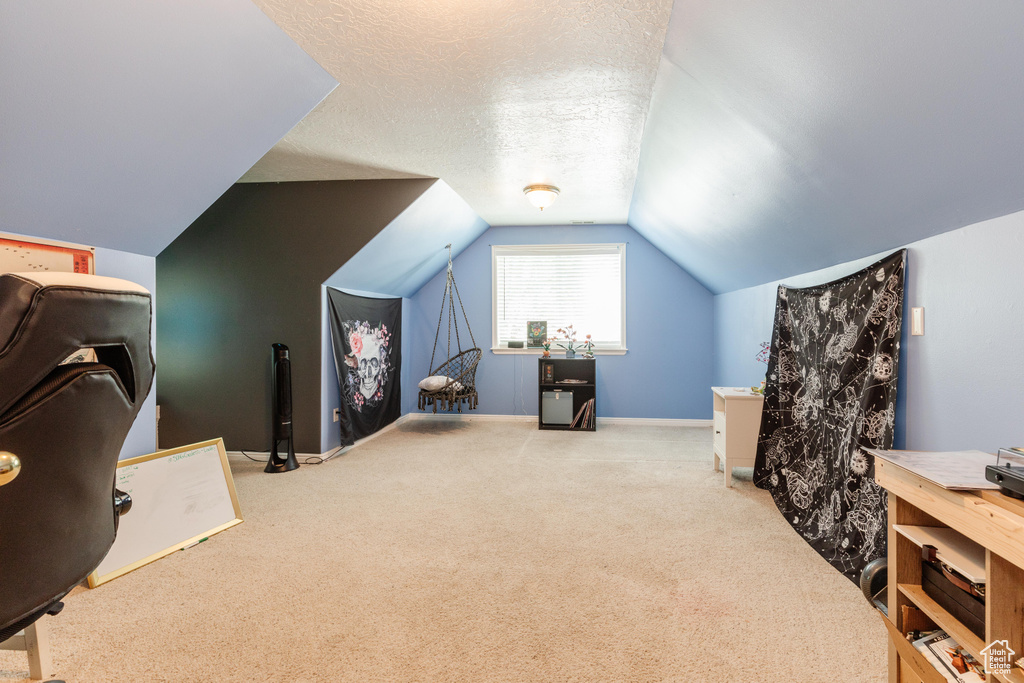 Interior space featuring carpet flooring, vaulted ceiling, a textured ceiling, and baseboards