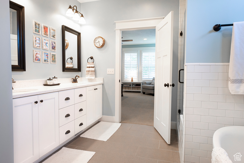 Bathroom with double vanity, tile walls, and a shower with shower door
