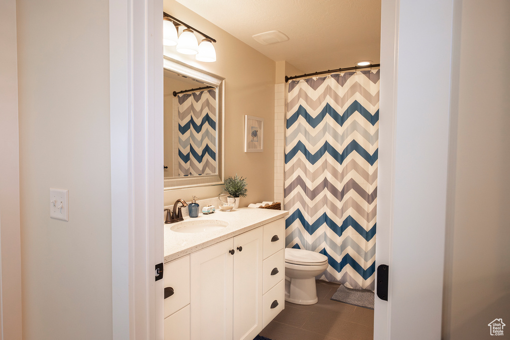 Bathroom featuring vanity, toilet, a shower with shower curtain, and tile patterned floors