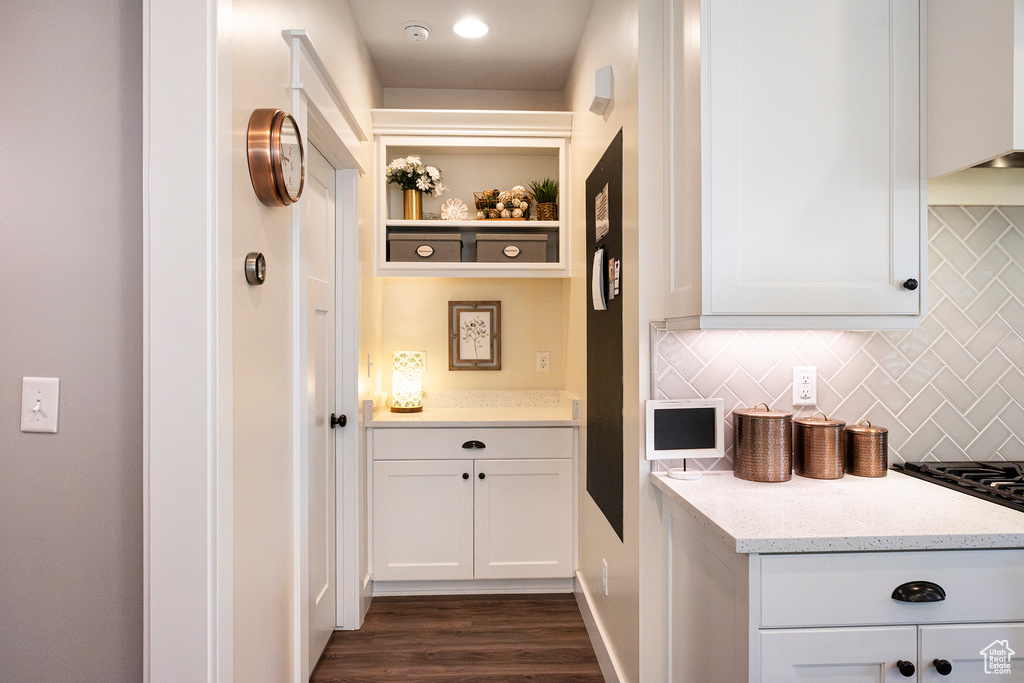 Kitchen with decorative backsplash, white cabinets, dark wood finished floors, and light stone counters