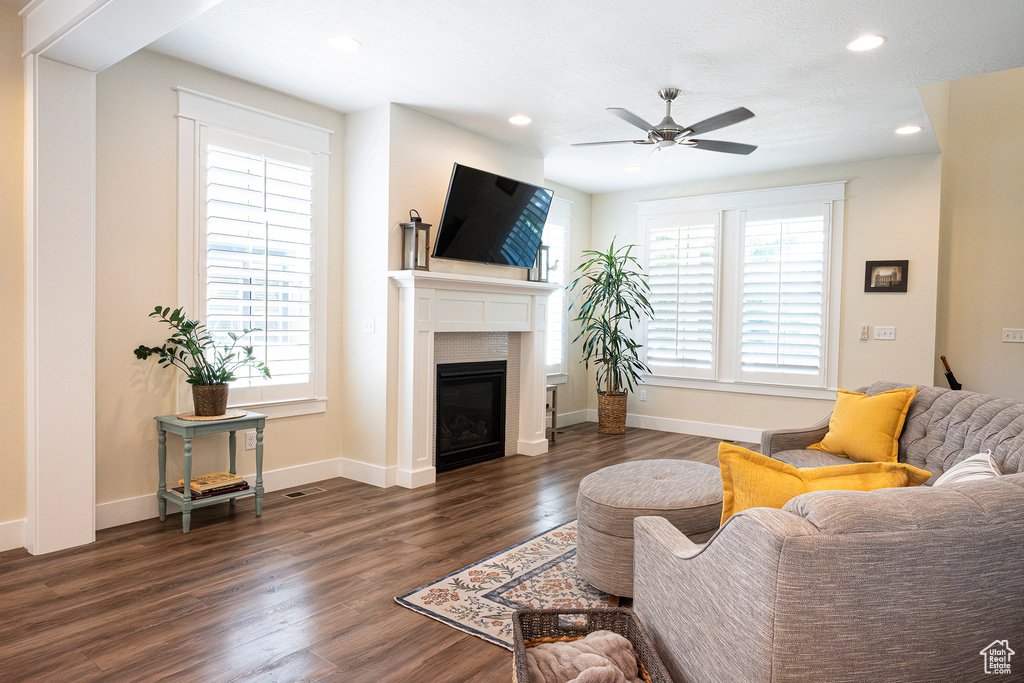 Living area featuring healthy amount of natural light, a ceiling fan, recessed lighting, dark wood-style floors, and a glass covered fireplace