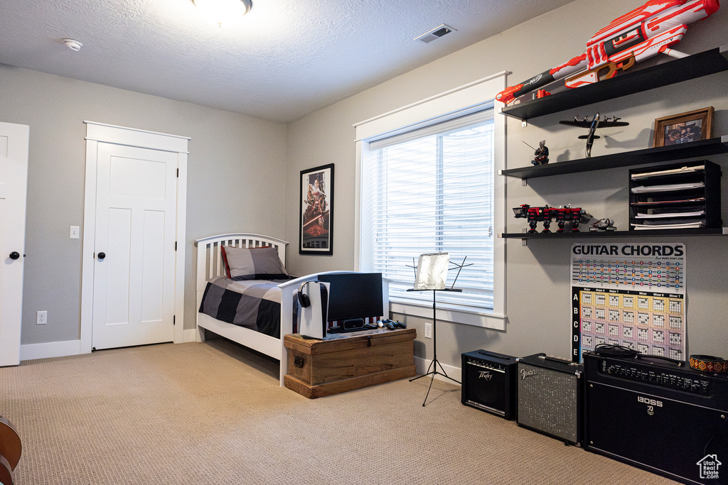 Carpeted bedroom featuring baseboards and a textured ceiling