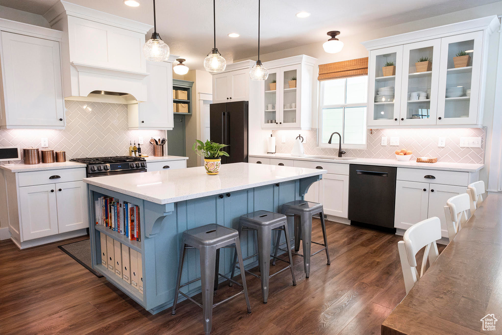Kitchen featuring dishwashing machine, freestanding refrigerator, a sink, a center island, and white cabinets