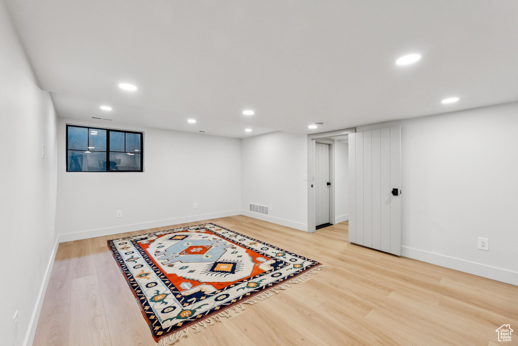 Finished basement with light wood-type flooring and recessed lighting