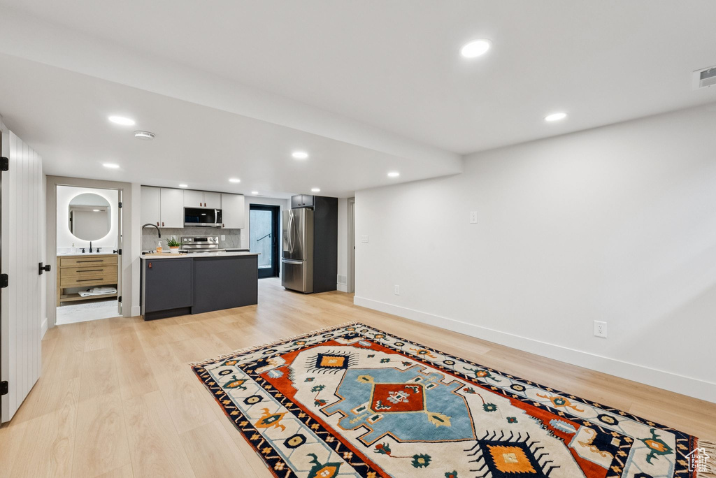 Kitchen with appliances with stainless steel finishes, light countertops, recessed lighting, light wood-style floors, and backsplash