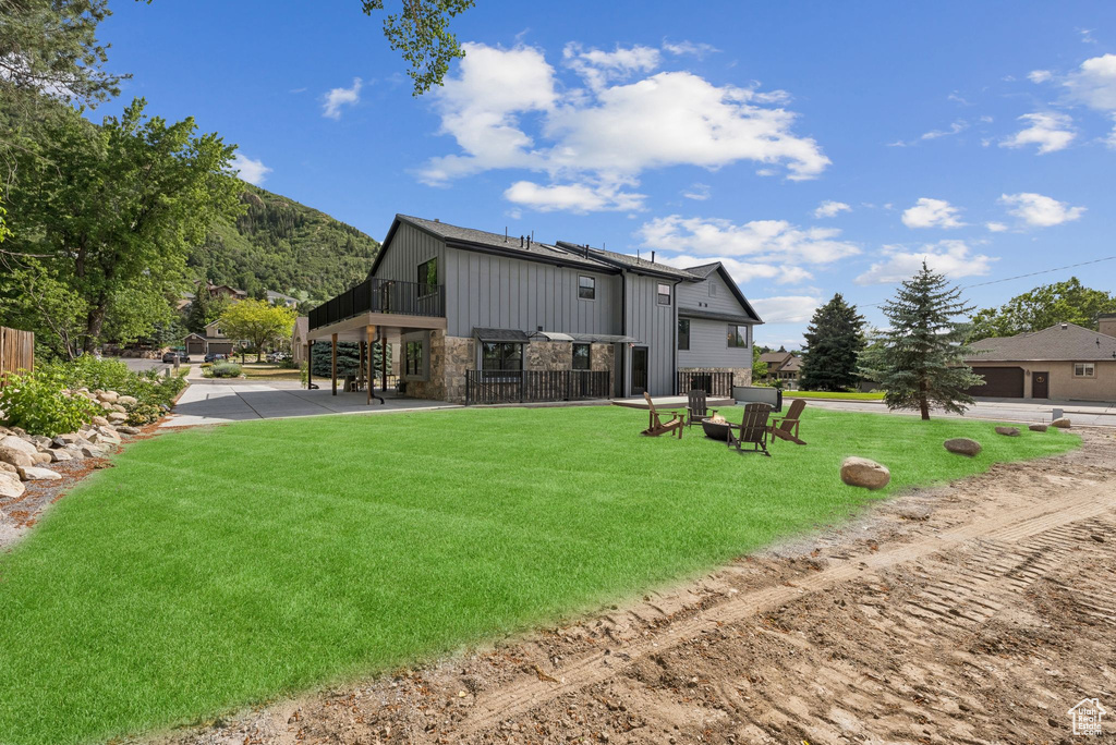 Back of property with stone siding, board and batten siding, and a lawn