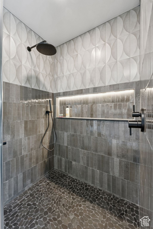 Bathroom featuring tiled shower and stone finish flooring