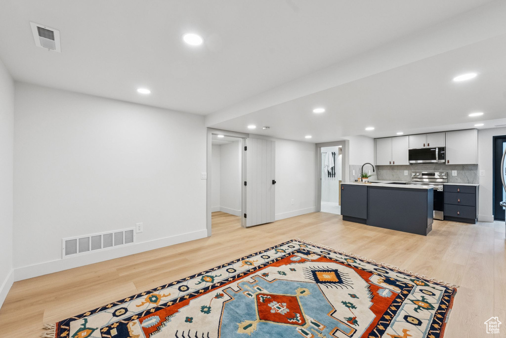 Kitchen with stainless steel appliances, light wood-style floors, light countertops, recessed lighting, and tasteful backsplash