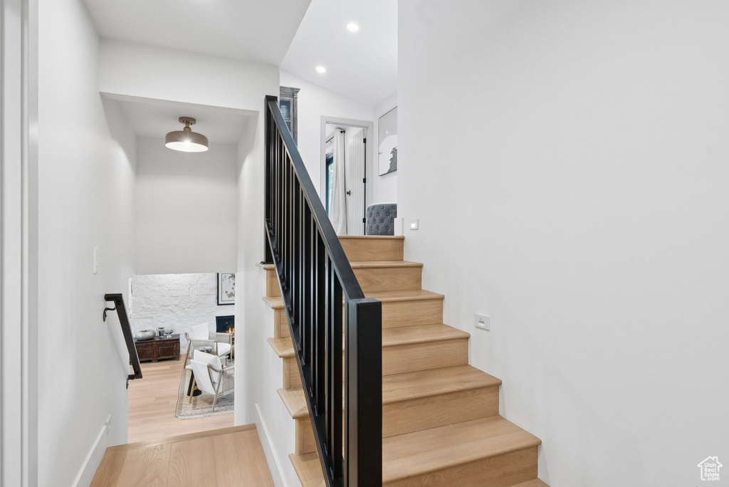 Stairs featuring wood finished floors, recessed lighting, and vaulted ceiling