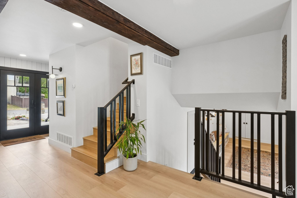 Stairs with wood finished floors, recessed lighting, beam ceiling, and french doors