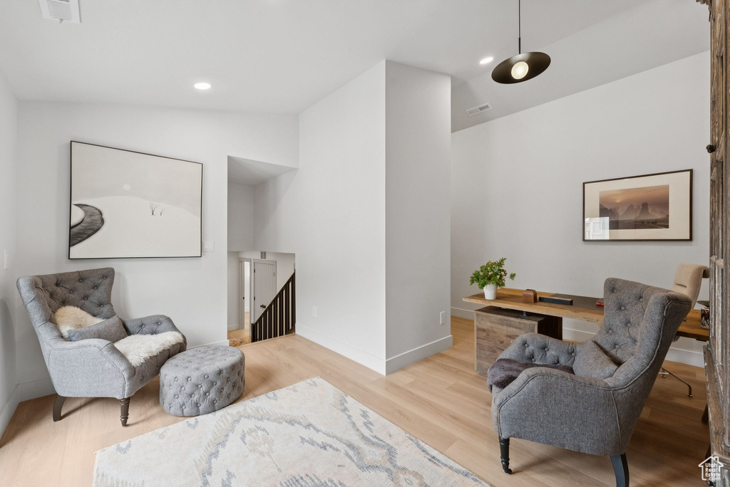 Sitting room with wood finished floors, recessed lighting, vaulted ceiling, and an upstairs landing