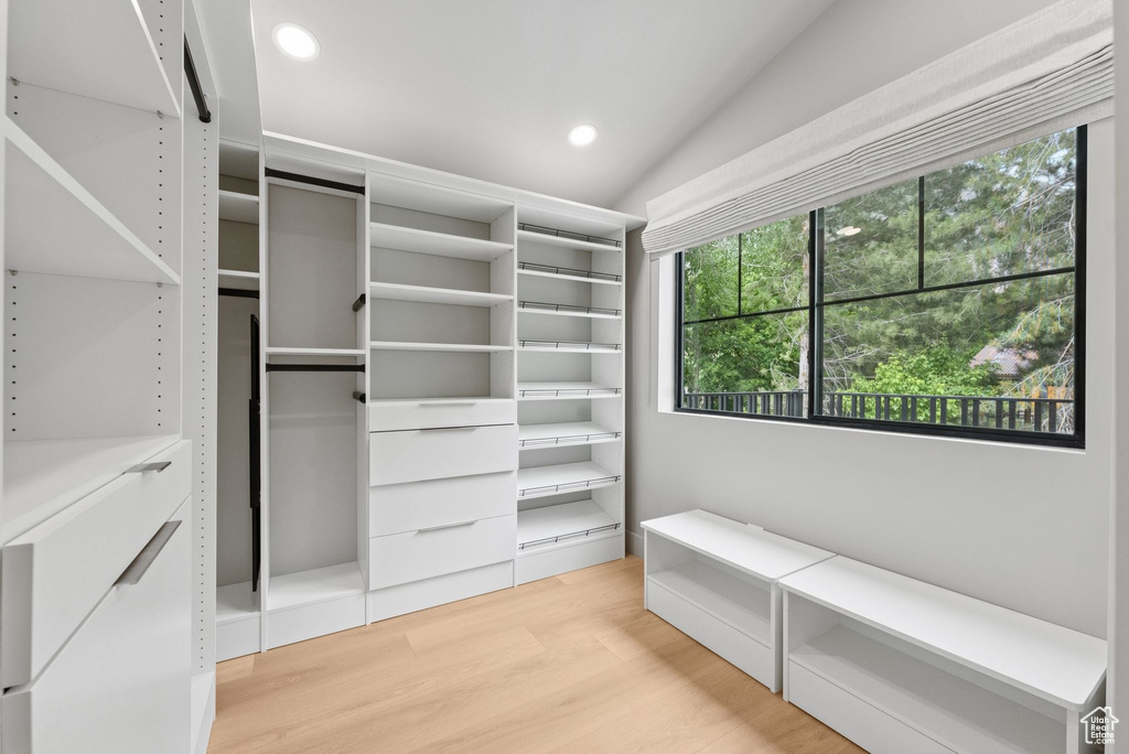 Spacious closet featuring light wood finished floors and lofted ceiling