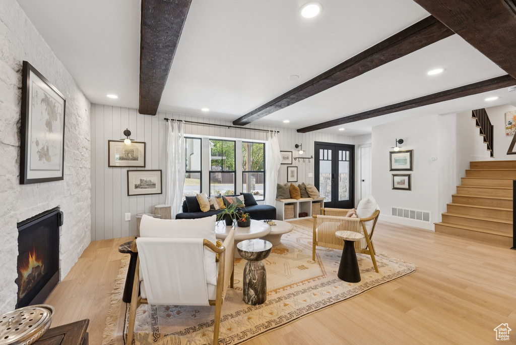 Living room featuring light wood-type flooring, stairs, recessed lighting, a fireplace, and beam ceiling