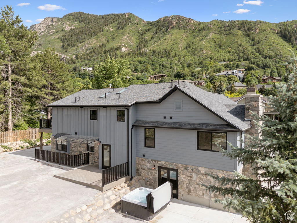 Rear view of property with a patio area, stone siding, a mountain view, board and batten siding, and a forest view
