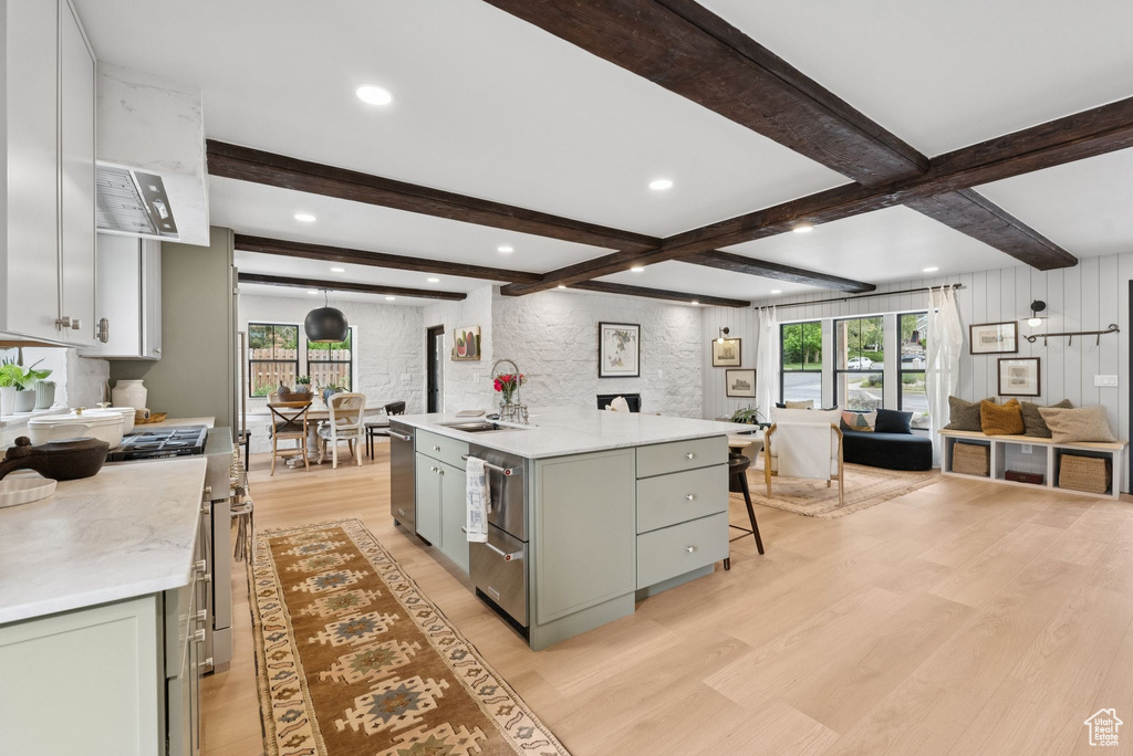 Kitchen featuring open floor plan, light wood-style flooring, gray cabinetry, light countertops, and beamed ceiling