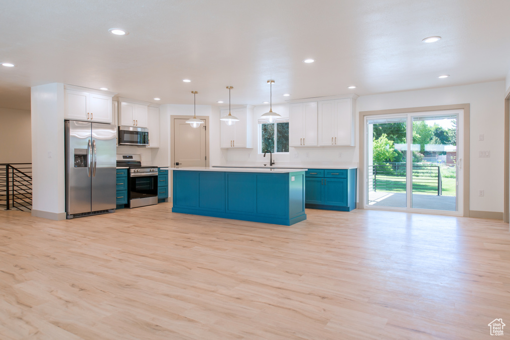 Kitchen with appliances with stainless steel finishes, light wood-style floors, recessed lighting, healthy amount of natural light, and white cabinets