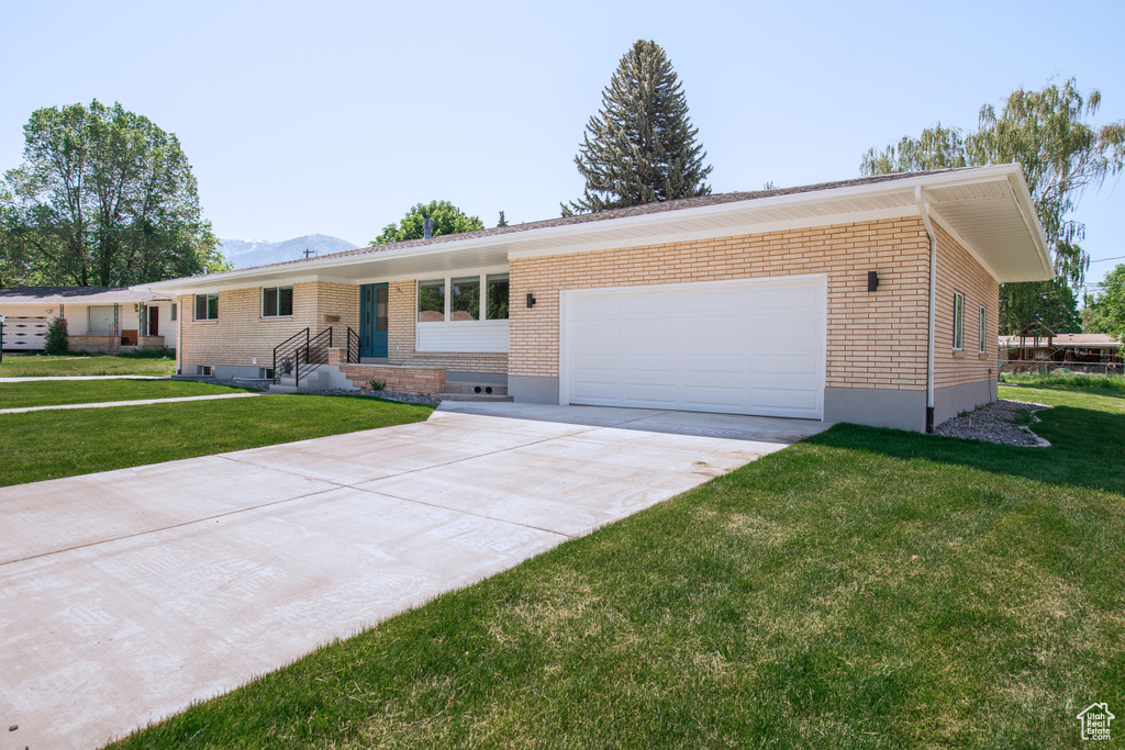 Ranch-style home featuring brick siding, an attached garage, driveway, and a front yard