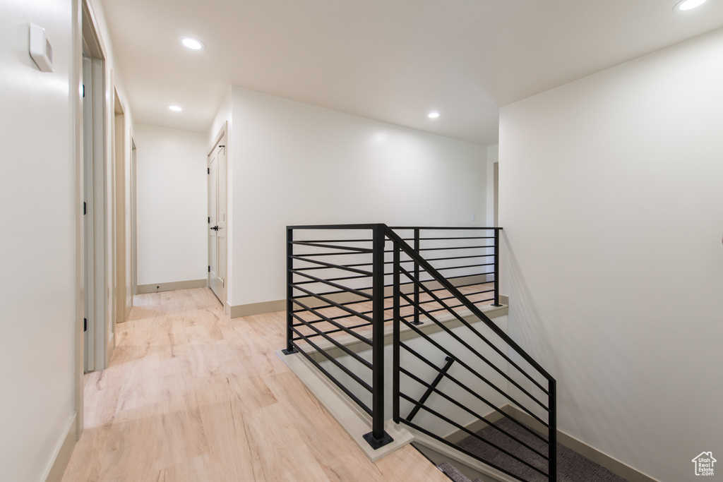 Hallway with an upstairs landing, wood finished floors, recessed lighting, and baseboards