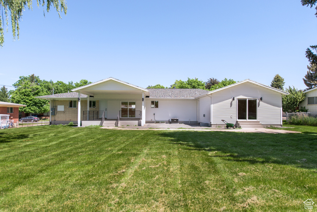 Back of property featuring entry steps, a lawn, a porch, and roof with shingles