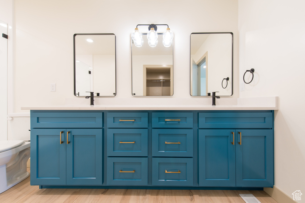 Full bath featuring double vanity, toilet, and wood finished floors