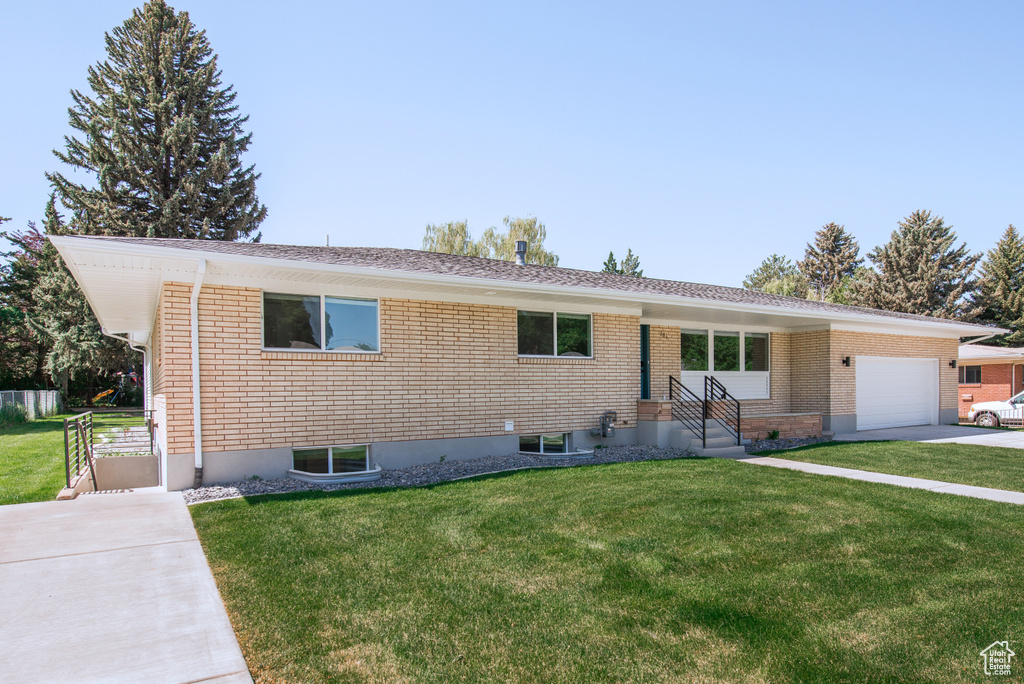 Single story home featuring a front yard, an attached garage, and concrete driveway