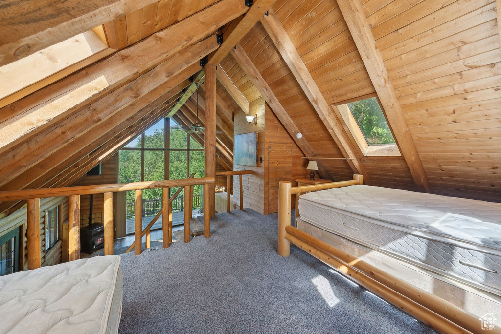 Unfurnished bedroom with wood ceiling, carpet, a skylight, and wooden walls