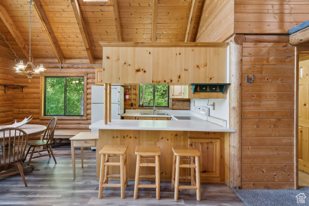 Kitchen with wooden ceiling, range, freestanding refrigerator, rustic walls, and a peninsula