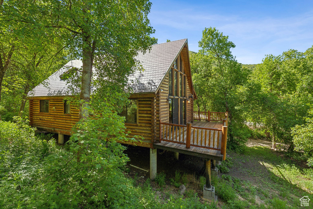 Back of property with a wooden deck and log siding