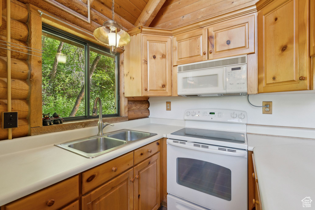 Kitchen featuring white appliances, a sink, light countertops, wood ceiling, and light brown cabinetry