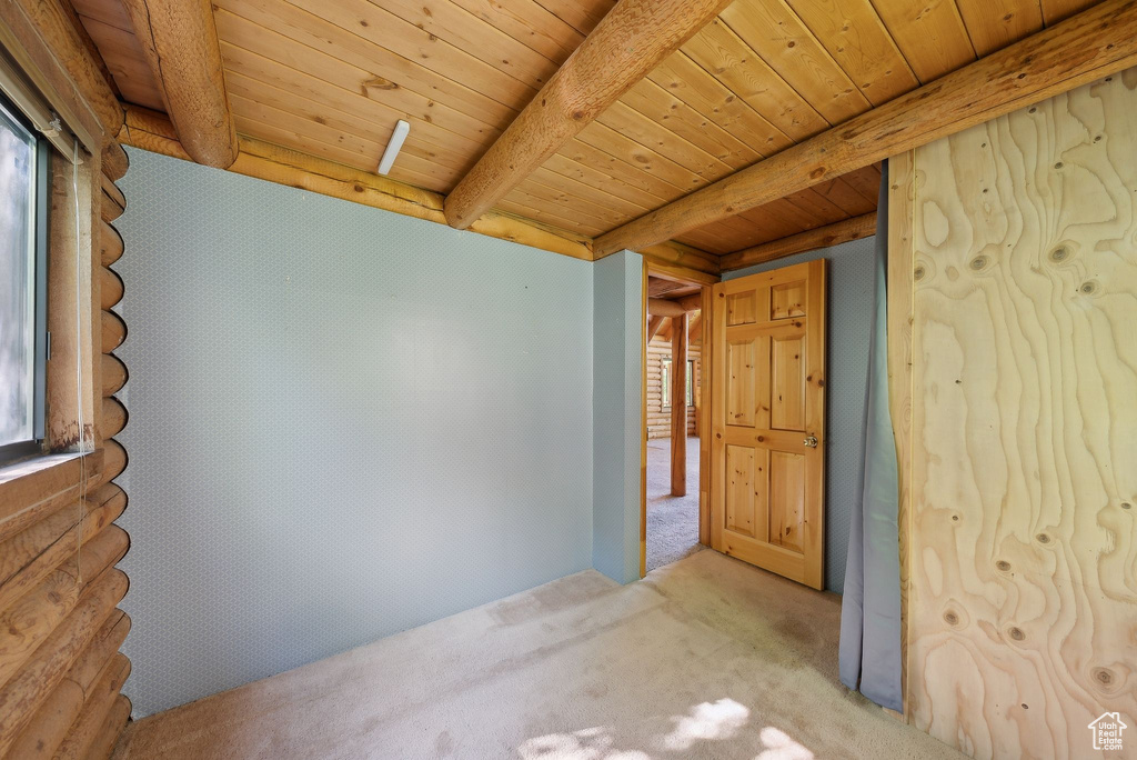Spare room with carpet flooring, wooden ceiling with exposed beams, and healthy amount of natural light